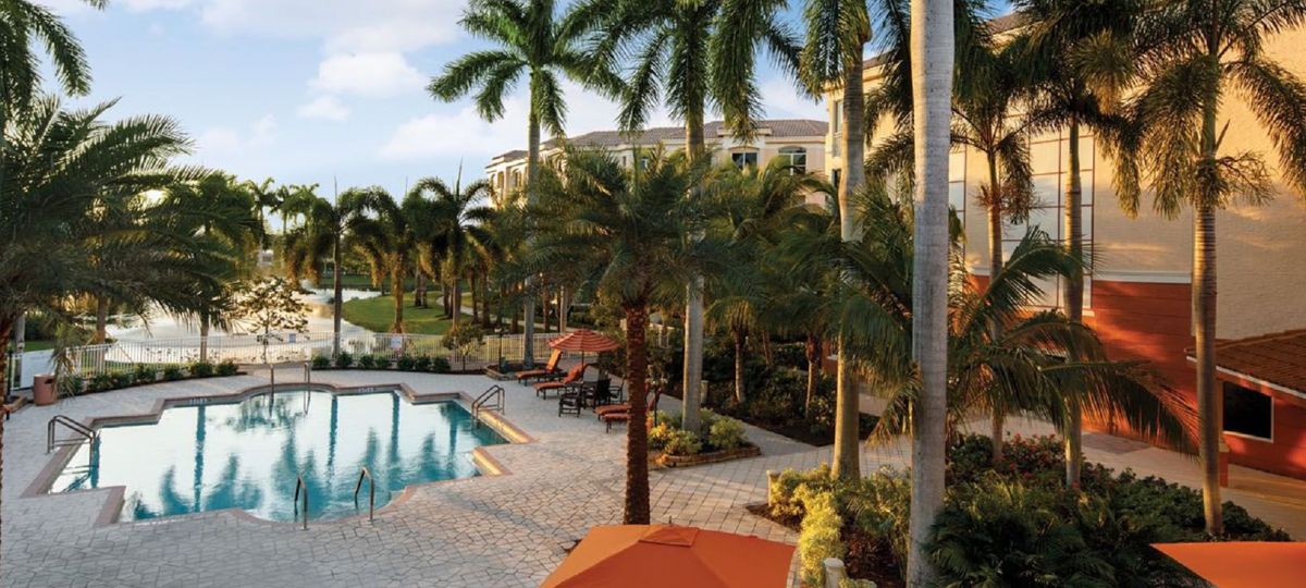 Luxurious swimming pool surrounded by palm trees at the premier Devonshire at PGA National in Palm Beach Gardens, Florida.