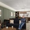 Cozy media lounge with built-in bookshelves, framed artwork, upholstered seating, and residents reading and chatting.