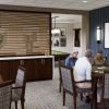 Interior rendering of a community game room with residents playing cards at tables, a pool table, and framed artwork.